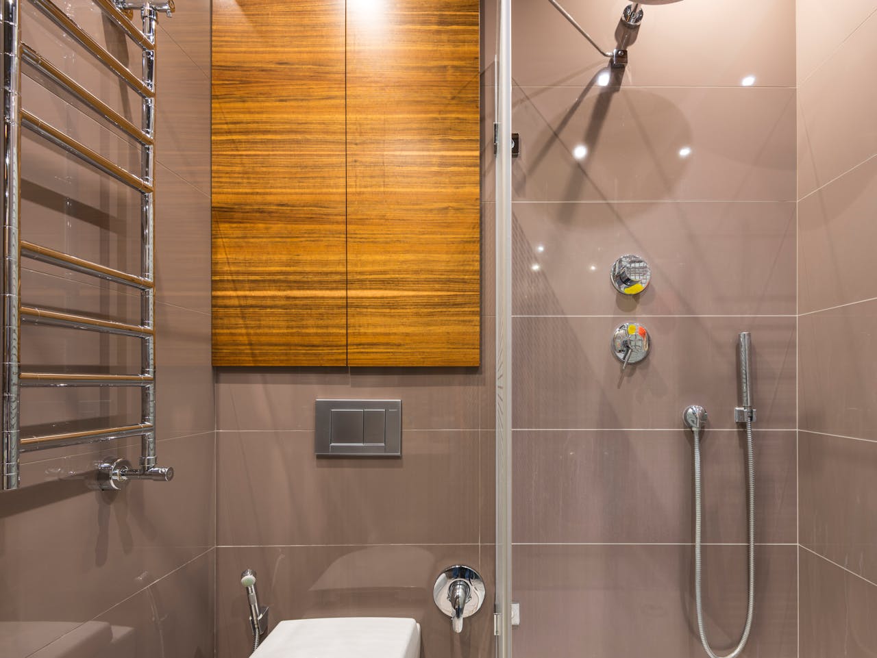 Elegant bathroom featuring a wooden cabinet, shower, and chrome fixtures, perfect for contemporary interiors.